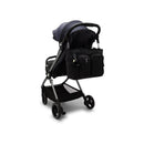 Convertible diaper backpack in Tiny Black Noir attached to a modern stroller, featuring multiple zippered pockets and a keychain accessory.