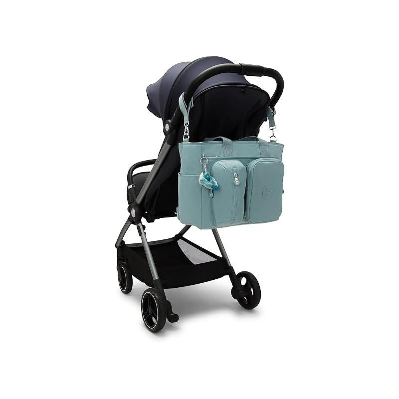 Kipling Babygear Convertible Diaper Backpack in Tiny Green Air attached to a stroller, featuring multiple compartments and a charm.