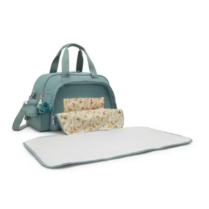 Kipling Camama Diaper Bag in Tiny Green Air with banana-patterned changing mat and accessories, featuring dual handles and a shoulder strap.