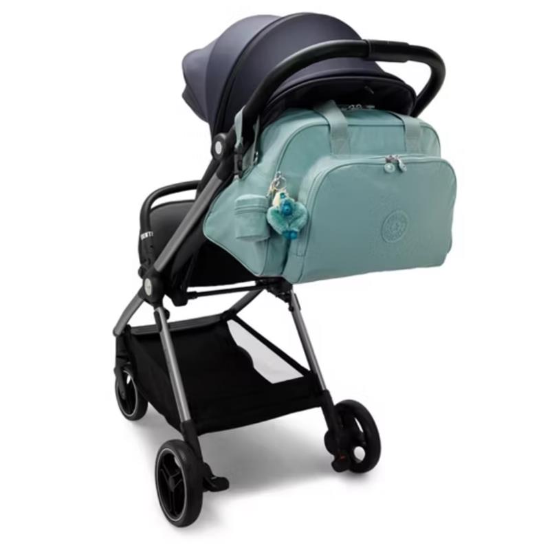 Kipling Camama Diaper Bag in Tiny Green Air attached to a stroller, featuring a blue keychain accessory.