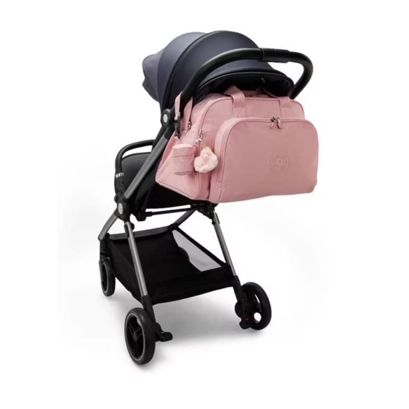 Kipling Camama Diaper Bag in Tiny Smoky Blush attached to a black stroller, featuring a pom-pom keychain.