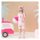 Baby girl in pink short sleeve pajamas with Barbie™ beach theme, holding a beach ball and wearing heart-shaped sunglasses.