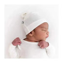 Bamboo baby knotted cap in cloud worn by an infant, who is resting against a white background.