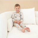 Toddler wearing Kyte Baby long sleeve pajamas with fluffy dog patterns, sitting comfortably on a white couch.