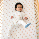 Baby wearing a Kyte Baby zippered footie with teddy bear print, lying on a crib sheet featuring teddy bear patterns.