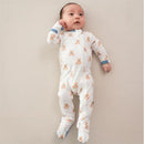 Baby wearing a Kyte Baby zippered footie with teddy bear prints, lying on a soft background.
