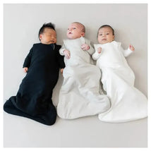 Three babies resting in bamboo sleep bags: one black, one grey, and one white, on a light background.
