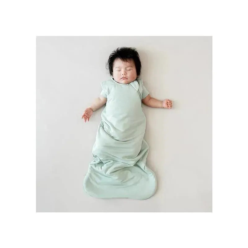 A peacefully sleeping baby in a sage green Kyte Baby bamboo sleep bag, showcasing the 1.0 Tog X-Small design.