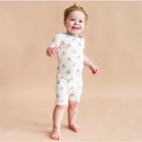 Toddler wearing Kyte Baby short sleeve pajamas featuring a teddy bear print, smiling against a neutral background.