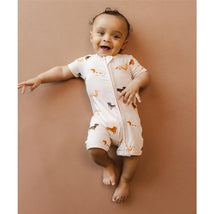 Infant wearing a Zipper Shortall Romper featuring playful dachshund prints, smiling while lying against a neutral background.
