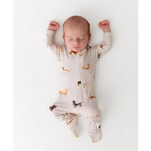 Zippered footie in dachshund print worn by a sleeping baby with arms raised, resting on a white background.