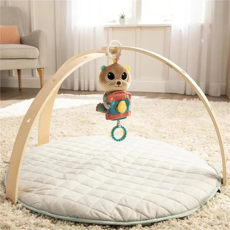 Lamaze Arty Says Cheese activity gym features a plush otter toy hanging from a wooden arch over a soft quilted mat.
