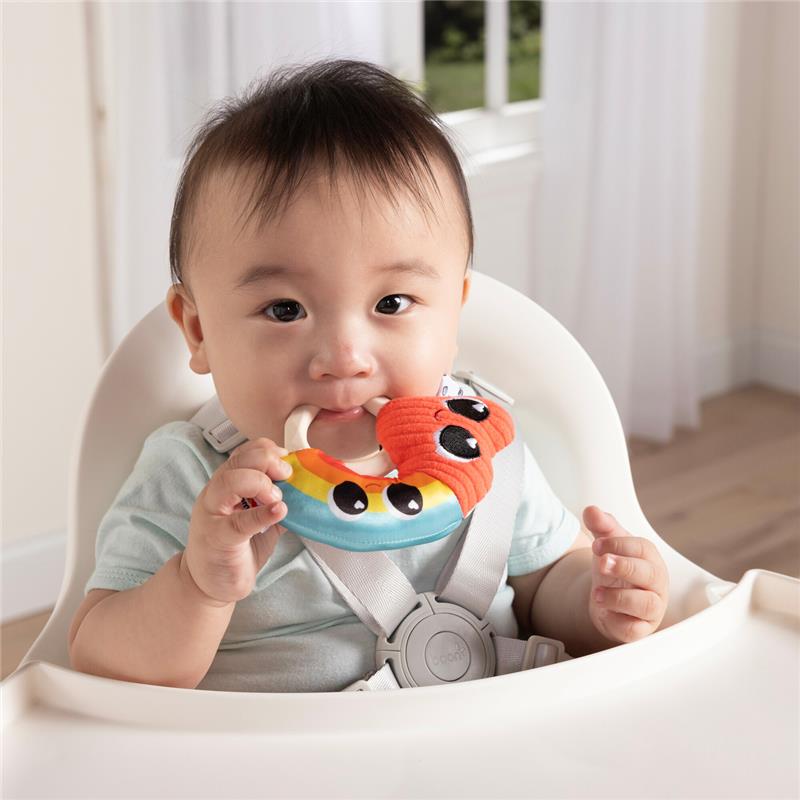 Baby seated in a high chair holding a colorful Lamaze Besties Rattle featuring a smiling creature and vibrant colors.