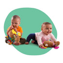 Two babies interact with the Lamaze Muffin the Moose toy, featuring colorful textures and sounds.