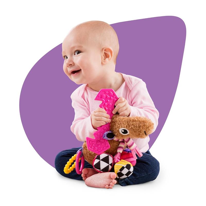 Baby joyfully holds the Lamaze Muffin the Moose toy with colorful features and textures, sitting on the floor.