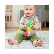 A happy baby sits on a soft rug, holding the vibrant Lamaze Fidget Fun Caterpillar toy featuring colorful segments and textures.