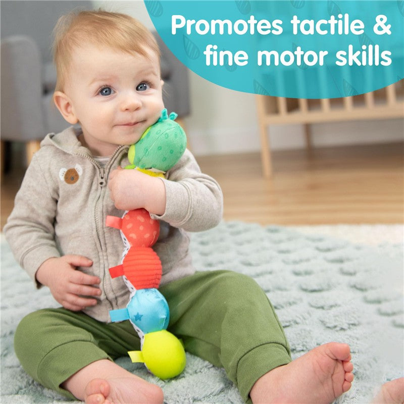 Toddler sitting on a soft rug, holding a colorful Lamaze Fidget Fun Caterpillar toy, promoting tactile and fine motor skills.