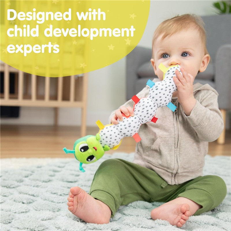Toddler seated on a soft rug, holding a colorful Lamaze Fidget Fun Caterpillar toy designed for child development.