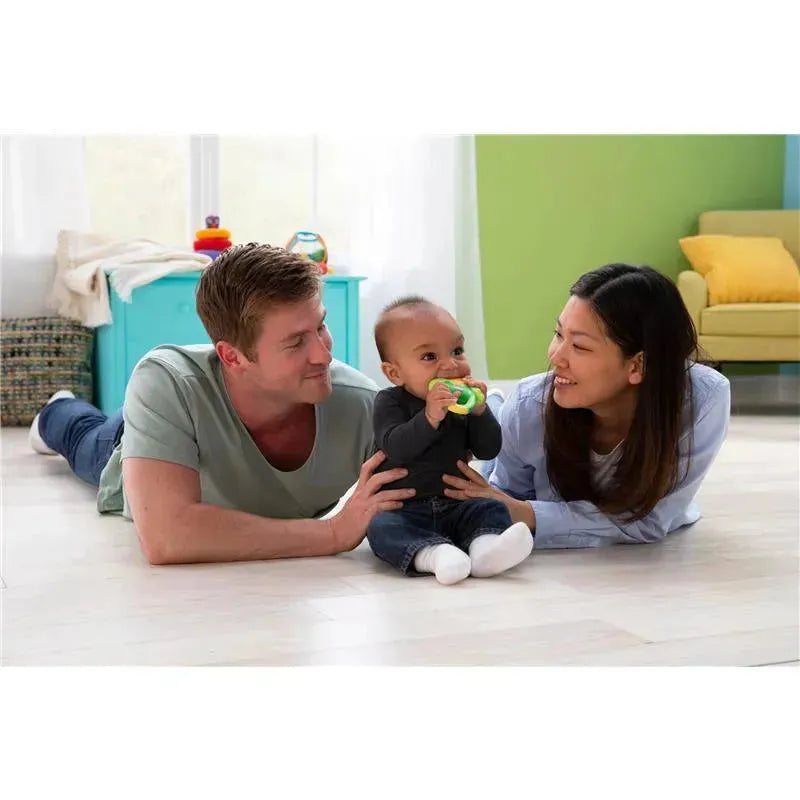 Family playing on the floor with the Lamaze John Deere Massaging Corn Teether, a baby in the center smiling while holding the teether.