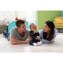 Family playing on the floor with the Lamaze John Deere Massaging Corn Teether, a baby in the center smiling while holding the teether.