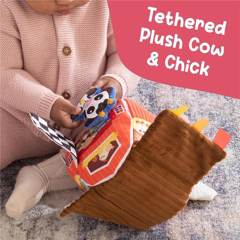 Tethered plush cow and chick toys are being explored by a child with a soft barn playset.