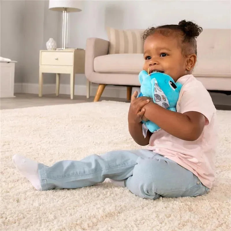 Toddler sitting on a plush carpet, hugging a blue Puffaboo™ Elephant sensory toy with patterned ears.