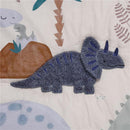 Blue and gray dinosaur plush applique on soft nursery bedding featuring a dino design, ideal for a baby crib.