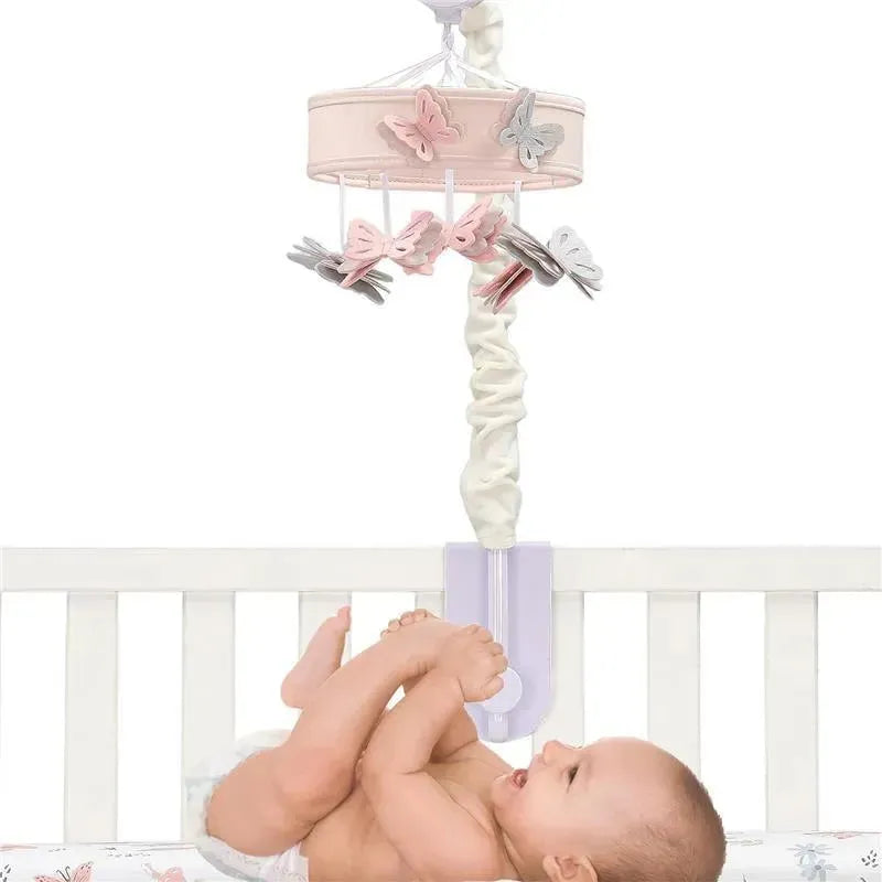 Pink butterfly musical crib mobile with hanging butterflies and a baby playing beneath it in a crib.