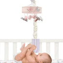 Pink butterfly musical crib mobile with hanging butterflies and a baby playing beneath it in a crib.