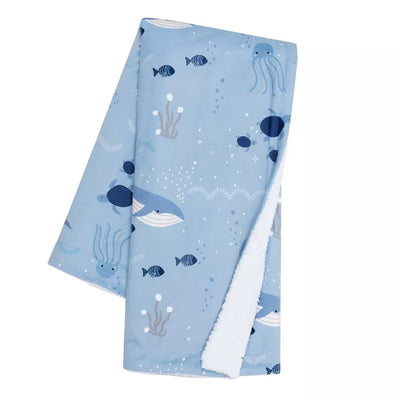 Lambs & Ivy Bubble & Squirt Baby Blanket features a light blue design with whales, fish, and sea creatures, lined with soft white fabric.