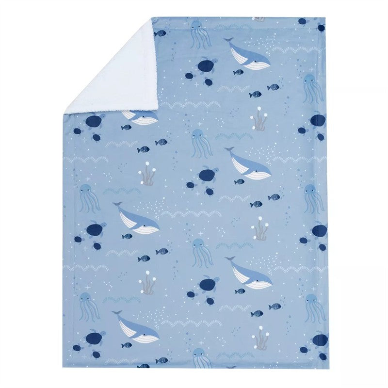 Soft blue baby blanket featuring whales, jellyfish, and ocean elements, with a plush white backing.