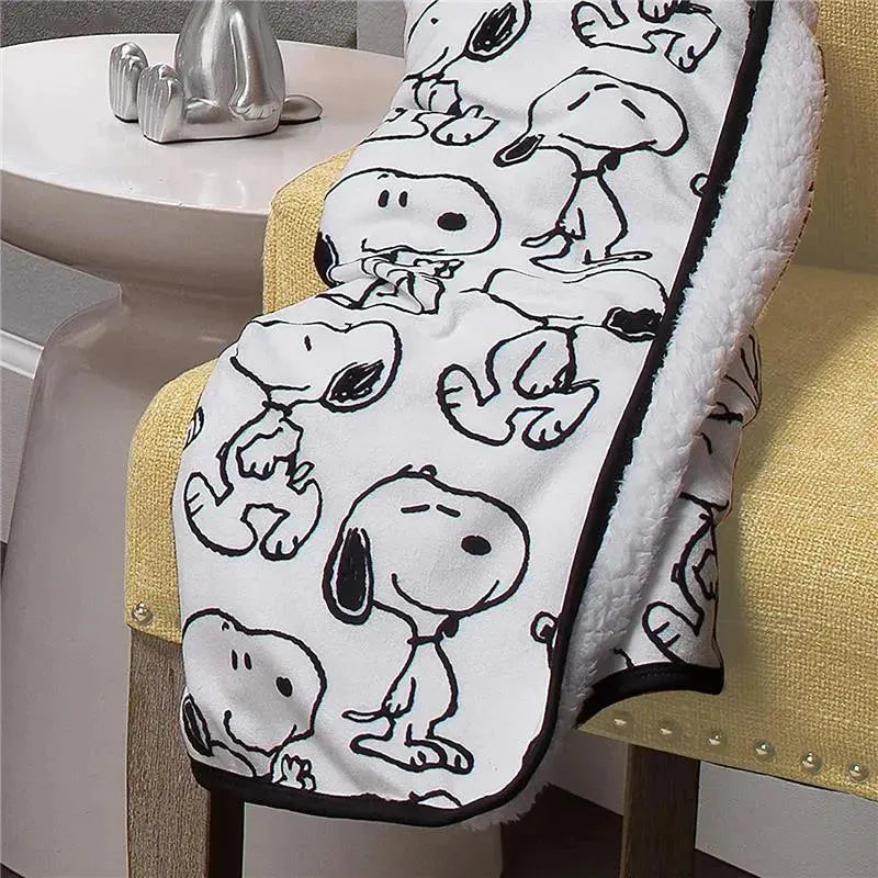 Snoopy blanket featuring black and white illustrations of the character on a soft, cozy fabric, draped over a chair.