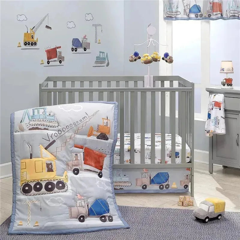 Fitted crib sheet featuring construction vehicles, complemented by a matching quilt and nursery decor in a soft color scheme.