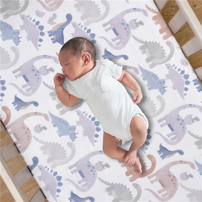 Fitted crib sheet featuring colorful dinosaur patterns with a sleeping baby in a white onesie.