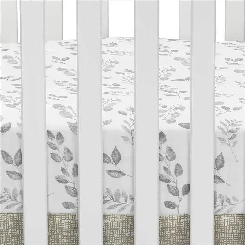 Fitted crib sheet with a painted forest design featuring gray leaves on a white background, displayed in a crib.