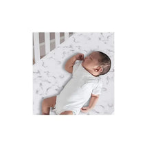 Gray marble fitted sheet on a crib with a baby wearing a light onesie, peacefully lying on it.