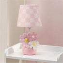 Lambs & Ivy Daisy Dreams lamp features a pink checkered shade and a base with colorful flower designs in pink and white.