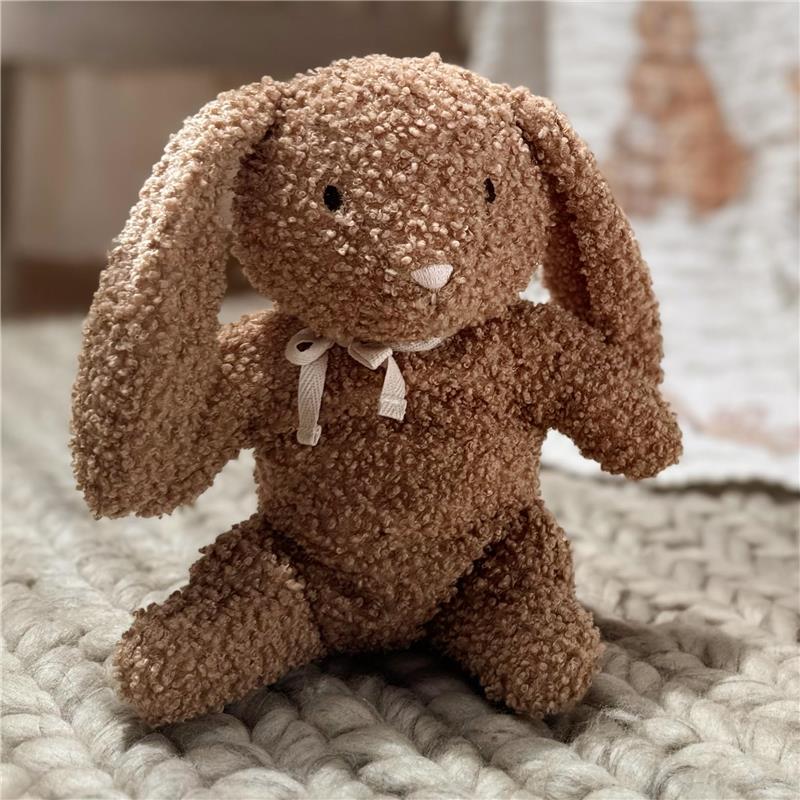 Organic cotton bunny plush in honey color, featuring floppy ears and a bow, sitting on a textured blanket.