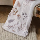 Blanket featuring a whimsical woodland design with a fox, flowers, and leaves, edged in soft white fabric.