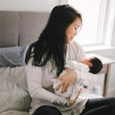 A woman gently cradles a newborn baby in a cozy setting, showcasing a tender moment of motherhood.