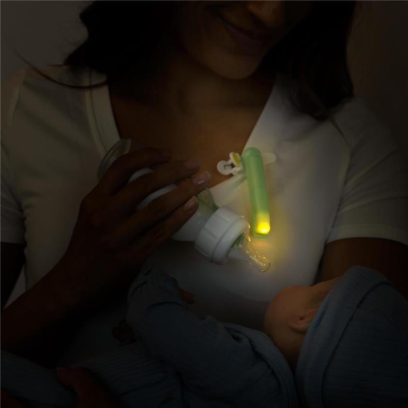 Latchlight Wearable Baby Night Light illuminating a bottle held by a parent feeding a baby in a dimly lit room.