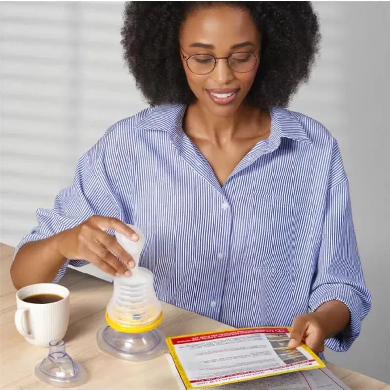 A woman in a striped shirt uses the Lifevac device while studying instructions on a leaflet, with a coffee cup nearby.