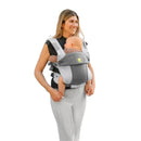 Líllé Baby Complete All Seasons Carrier in Pebble Grey worn by a woman carrying a baby, showcasing comfort and style.