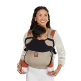 Líllébaby Elevate 6-In-1 Linen Blend Baby Carrier in Warm Sand, worn by a woman carrying a baby securely.