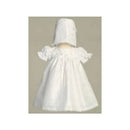 White short dress for baby girls with lace yoke, puff sleeves, and a matching bonnet.