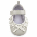 Ankle strap shoe in white with lace trim and bow detail, designed for infants.