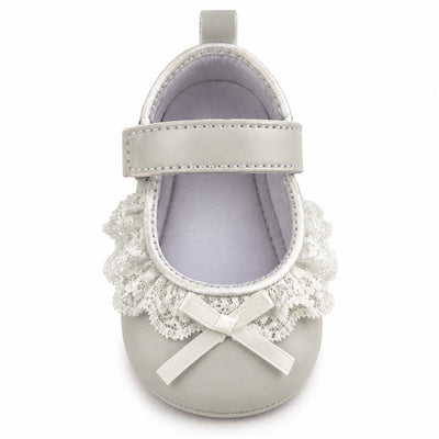 Ankle strap shoe in white with lace trim and bow detail, designed for infants.