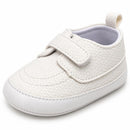 Single strap white baby boy shoe with textured fabric and a white rubber sole, designed for infants.