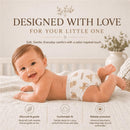 Baby lying on a bed wearing Little Me Safari Soft Diapers with animals printed on it, smiling with a gentle background.