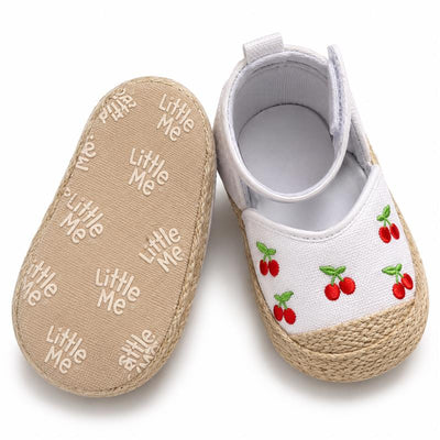 Espadrille-style baby girl sandals by Little Me, featuring white fabric with embroidered cherries and a textured sole.
